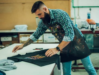 male worker folding a fresh printed t shirt in a p 2022 04 15 20 31 15 utc 1